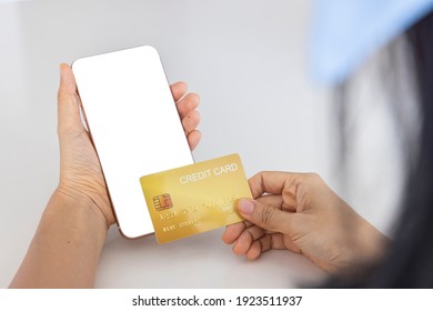 A Woman Shopping Online On Her Sofa At Home With A Smartphone Using A Gold Credit Card. And Use Your Credit Card To Tap The Screen To Verify The Identity. Concept About Business. Over Shoulder Shot.