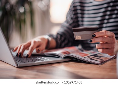 Woman Shopping Online And Using Credit Card While Reading Cosmetic Catalogue