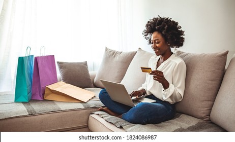 Woman shopping online while chilling at home on the sofa. I have enough cash to spend. Happy girl with shopping bags. Cropped shot of a woman using her credit card to make an online payment