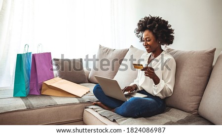 Woman shopping online while chilling at home on the sofa. I have enough cash to spend. Happy girl with shopping bags. Cropped shot of a woman using her credit card to make an online payment