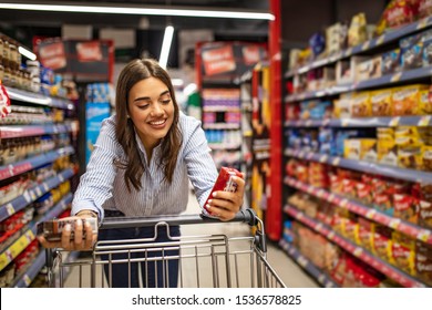 Woman With Shopping Trolley In Supermarket Aisle. Buying Food In Grocery Store. Grocery Shopping. Beautiful Young Woman Shopping In A Grocery Store/supermarket 