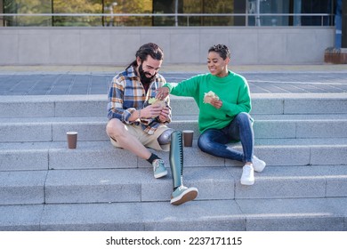 Woman with short hair and man with long hair and prosthetic leg spending some time together outdoors - Powered by Shutterstock