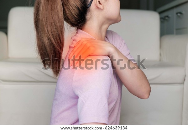 woman with\
shoulder pain or stiffness.Acute pain in a woman shoulder. Female\
holding hand to spot of shoulder-aches. Concept photo  with read\
spot indicating location of the\
pain.