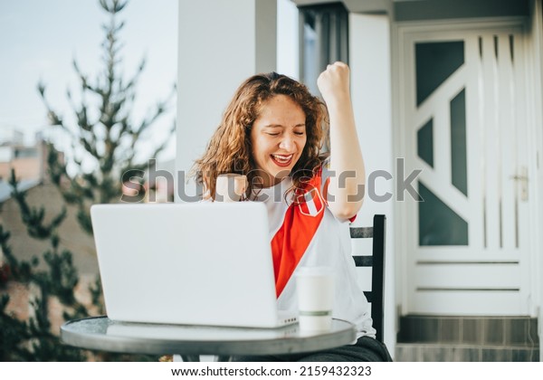 Woman shouting goal while working on\
her laptop, concept of sports and reactions.\
(Peru)
