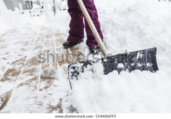 A woman\
shoveling and removing snow\
outside