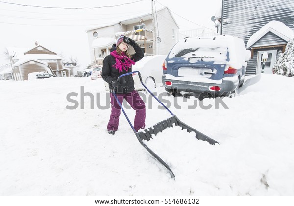 A woman\
shoveling and removing snow\
outside