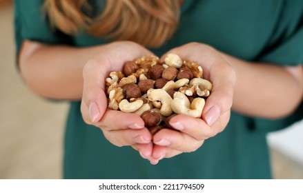 Woman showing abundance and variety of nuts mix of dried fruits in her hands - Shutterstock ID 2211794509