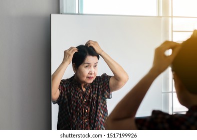 Woman Showing Black Gray Hair Roots On Her Head At Front Of Mirror,Close Up