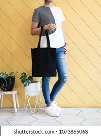 Woman Showing Black Totebag. Tote Bag Mock Up For Designer. In Fun Background, Pink Yellow And Green Pallete