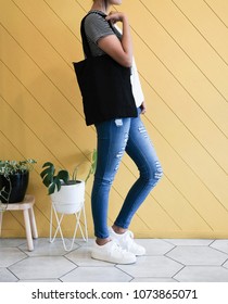 Woman Showing Black Totebag. Tote Bag Mock Up For Designer. In Fun Background, Pink Yellow And Green Pallete