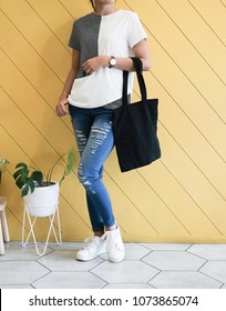 Woman Showing Black Totebag. Tote Bag Mock Up For Designer. In Fun Background, Pink Yellow And Green Pallete