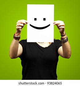 Woman Showing A Blank Paper With A Smile Emoticon In Front Of Her Face Against A Green Background