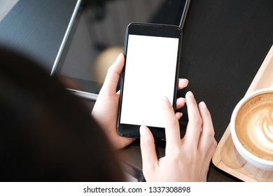 Woman is showing digital cell phone  blank screen on work desk in coffee shop. - Shutterstock ID 1337308898