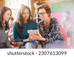 Woman showing digital tablet to women in community center