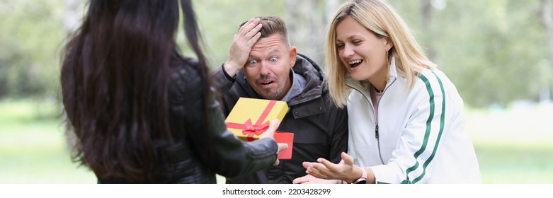 Woman Showing Gift Box To Shocked Friends. Emotions Of Joy And Enthusiasm Concept