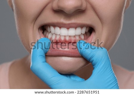 Woman showing healthy gums on gray background, closeup