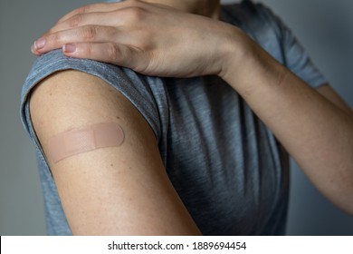 A woman showing her arm with an adhesive bandage after injection of vaccine or a scratch on the skin. First aid. Medical, pharmacy, and healthcare concept. After vaccination treatment. - Powered by Shutterstock