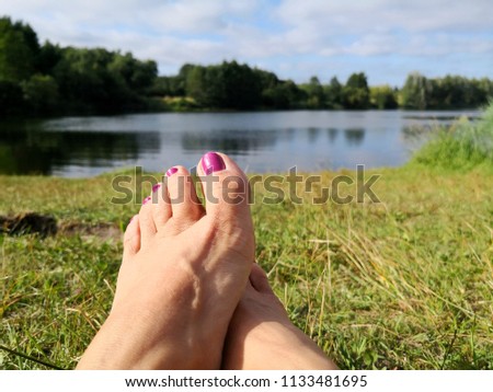 woman showing her feet with painted nails at the artificial lake summer fun 