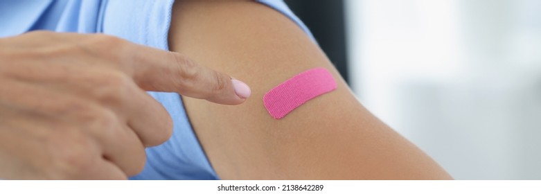 Woman Showing Her Index Finger To Patch At Injection Site Of Flu Vaccine Closeup