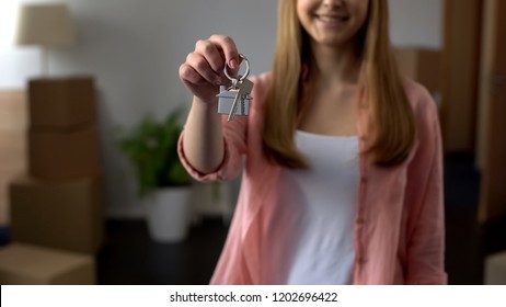 Woman showing key from apartment, affordable lending, investment in real estate