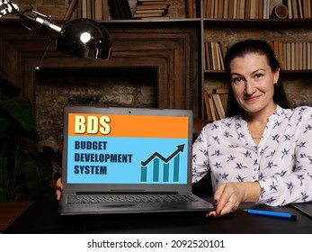 Woman showing laptop computer with  BDS BUDGET DEVELOPMENT SYSTEM icon on screen background, success in business concept