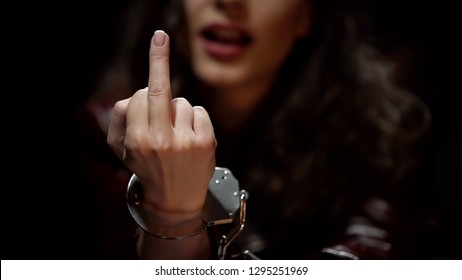 Woman showing middle finger to detective during interrogation, indecent gesture