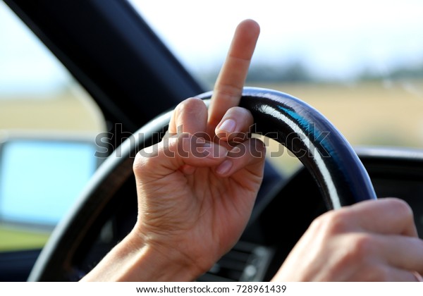 Woman\
showing the middle finger at steering wheel in\
car