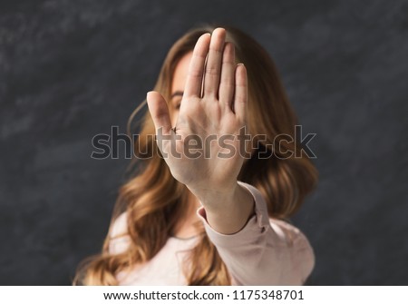 Woman showing no with her hand. Stop sign of discrimination or anti violence symbol, black studio background, copy space