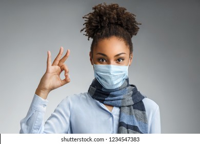 Woman Showing Okay Gesture. Photo Of Healthy African American Woman Wears Protective Mask Against Infectious Diseases And Flu. Health Care Concept.