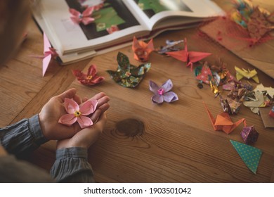 Woman showing origami in hand at home