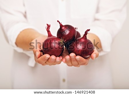 Woman showing red onions in her hands
