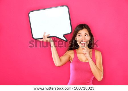 Woman showing sign speech bubble banner looking happy excited on pink background. Beautiful young multiracial Caucasian / Asian Chinese joyful model on pink background having idea.