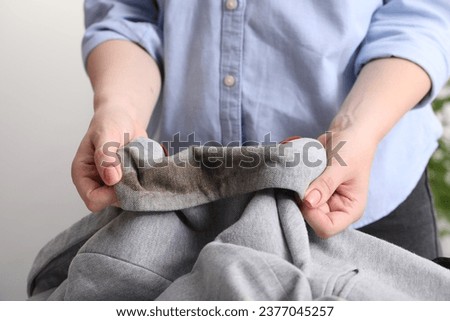 Woman showing stain from coffee on jacket against blurred background, closeup