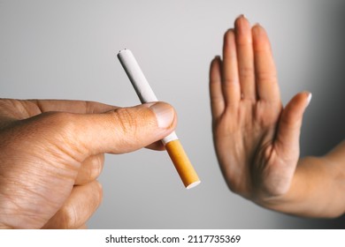 Mujer mostrando el cartel de alto con la mano y negándose a tomar un cigarrillo. No fumar o dejar de fumar