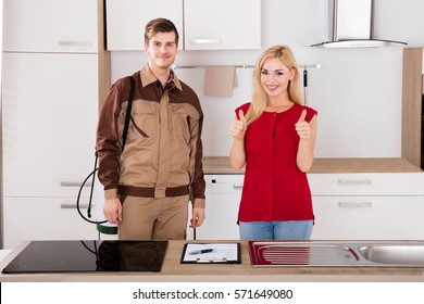 Woman Showing Thumbs Up With Pest Control Exterminator Service Worker Standing In Kitchen