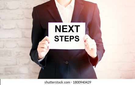 woman showing white card with NEXT STEPS word . Business concept