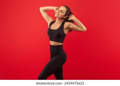 A woman is shown wearing a black sports bra top and matching leggings. She appears to be engaged in physical exercise or fitness activities, showcasing strength and determination in her outfit. - Powered by Shutterstock