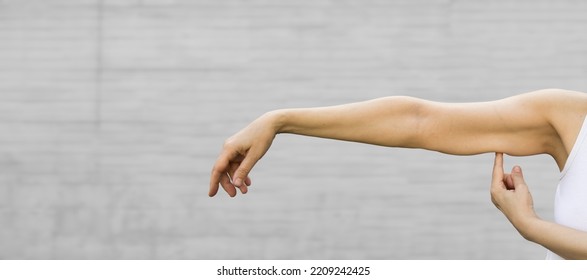 A woman shows the flabby muscles of the arm . Flabby Arm Syndrome (FAS). Effect of aging caused by loss of elasticity and muscle.Banner, copyspace. - Shutterstock ID 2209242425
