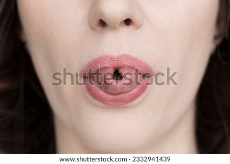 A woman shows her tongue folded into a tube, close-up.