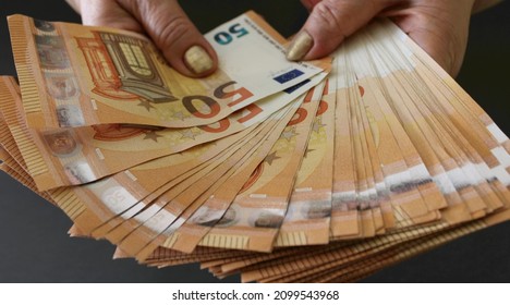 Woman shows a stack of money of 50 euro banknotes on a grey background. Woman holding euro money in hands. Close up view.
