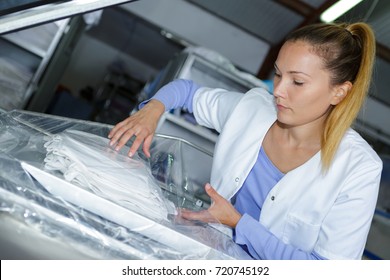 Woman Shrink Wrapping Clean Laundry In Plastic