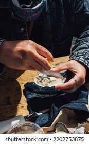 Woman Shucking And Eating Oysters At Outdoor Restaurant 