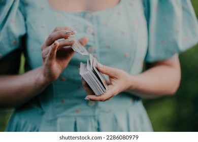 Woman shuffles tarot deck, preparation for consultation on predicting future destiny. Fortune teller, medium, divination cards.