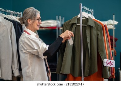 Woman Sideways To Camera Touching Blouse On Hanger