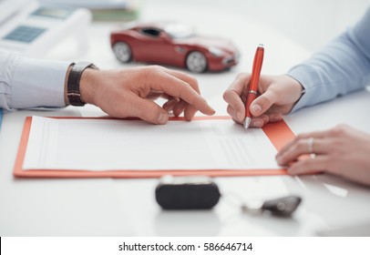 Woman Signing A Car Insurance Policy, The Agent Is Pointing At The Document