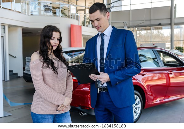 Woman signing\
contract with dealer in\
showroom