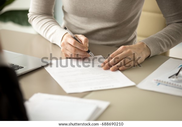 Woman signing document, focus on female hand holding\
pen, putting signature at official paper, subscribing name in\
statement with legal value, contract management, good business\
deal, close up view