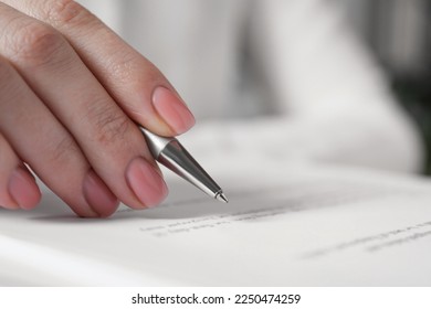 Woman signing document at table in office, closeup - Shutterstock ID 2250474259