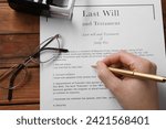 Woman signing Last Will and Testament at wooden table, above view