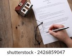 Woman signing Last Will and Testament at wooden table, top view. Space for text